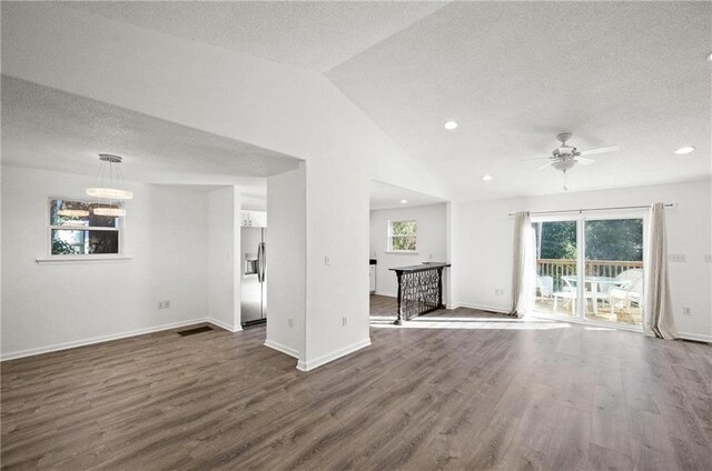 unfurnished living room with ceiling fan, dark wood-type flooring, vaulted ceiling, and a textured ceiling