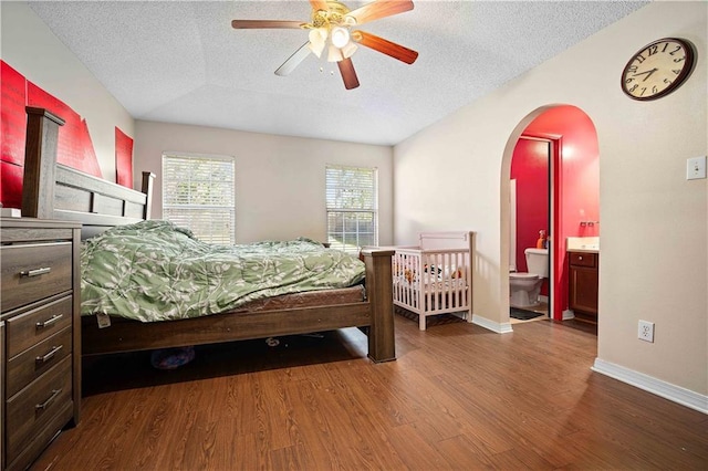 bedroom with lofted ceiling, dark wood-type flooring, ensuite bath, ceiling fan, and a textured ceiling