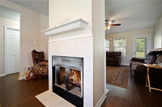 living room with a fireplace, ceiling fan, dark hardwood / wood-style flooring, and a textured ceiling