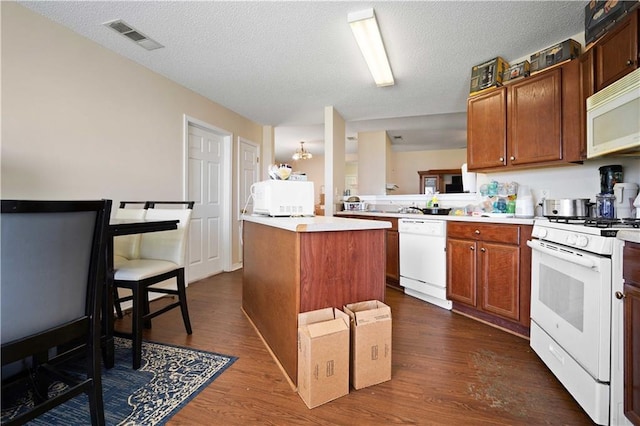 kitchen featuring a textured ceiling, white appliances, a kitchen island, and dark wood-type flooring