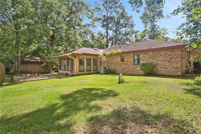 back of property featuring a sunroom, a yard, and central AC unit