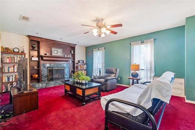 carpeted living room featuring a fireplace and ceiling fan