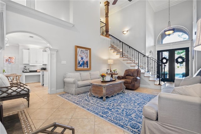 living room featuring a towering ceiling, french doors, ceiling fan, ornamental molding, and light tile patterned floors