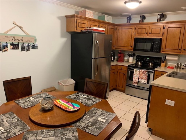 kitchen featuring crown molding, sink, light tile patterned floors, and stainless steel appliances