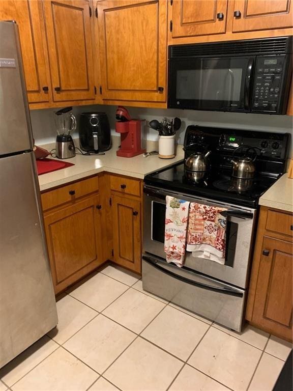 kitchen with light tile patterned flooring, electric stove, and stainless steel refrigerator