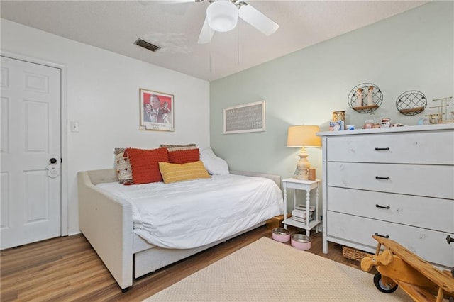 bedroom with visible vents, a ceiling fan, and wood finished floors