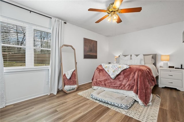 bedroom with ceiling fan, baseboards, and wood finished floors