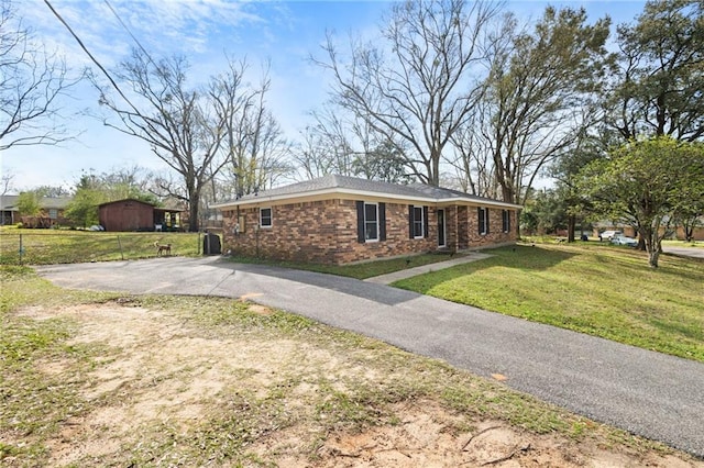 view of front of house with a front lawn, fence, brick siding, and driveway