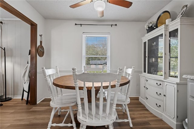 dining room featuring dark wood-type flooring, a ceiling fan, and a textured ceiling