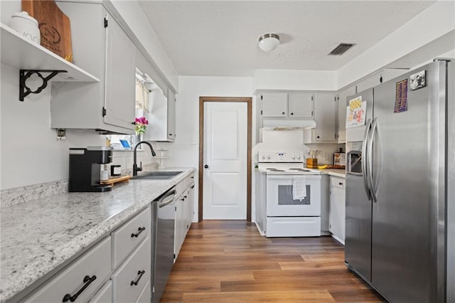 kitchen with wood finished floors, visible vents, a sink, under cabinet range hood, and appliances with stainless steel finishes