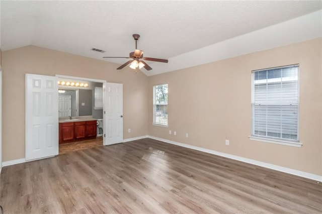 unfurnished bedroom featuring ensuite bathroom, lofted ceiling, sink, ceiling fan, and light hardwood / wood-style floors