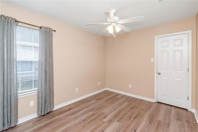 unfurnished room featuring ceiling fan, a wealth of natural light, a textured ceiling, and light wood-type flooring