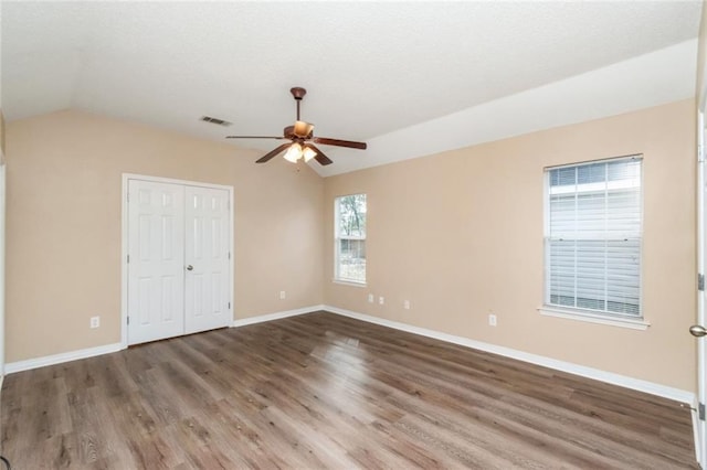 unfurnished bedroom featuring vaulted ceiling, dark hardwood / wood-style flooring, ceiling fan, and a closet