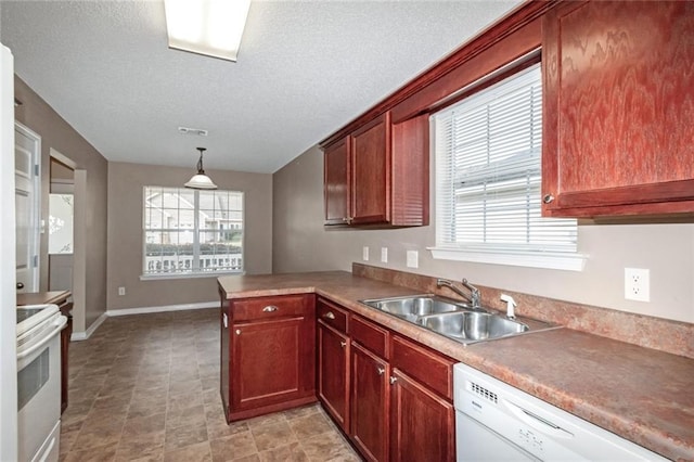 kitchen featuring sink, white appliances, a textured ceiling, decorative light fixtures, and kitchen peninsula