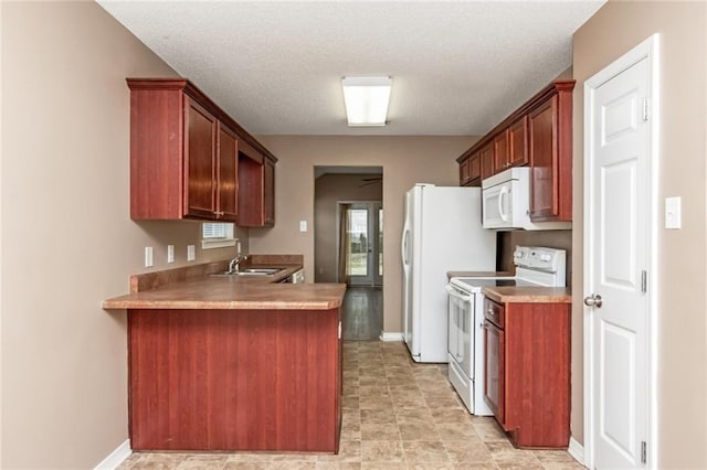 kitchen featuring sink, white appliances, kitchen peninsula, and a textured ceiling