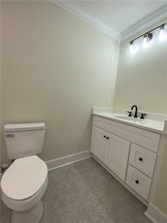 bathroom featuring vanity, toilet, and crown molding