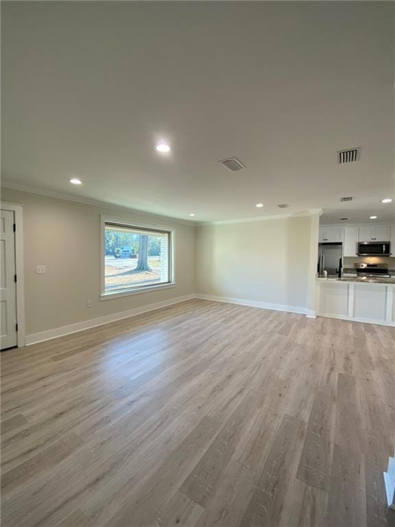 unfurnished living room featuring light hardwood / wood-style floors and crown molding