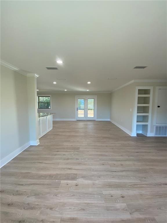 unfurnished living room with built in shelves, light wood-type flooring, and crown molding