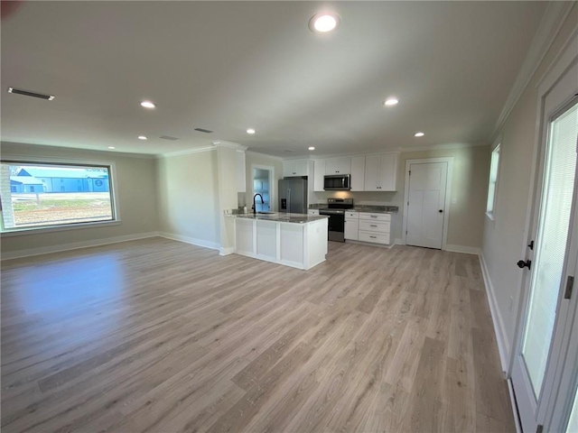 kitchen with a healthy amount of sunlight, kitchen peninsula, white cabinetry, and stainless steel appliances