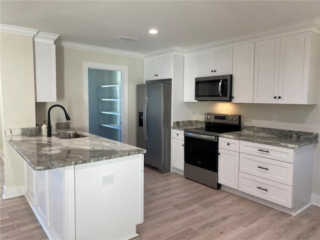 kitchen with white cabinetry, kitchen peninsula, appliances with stainless steel finishes, and light hardwood / wood-style flooring