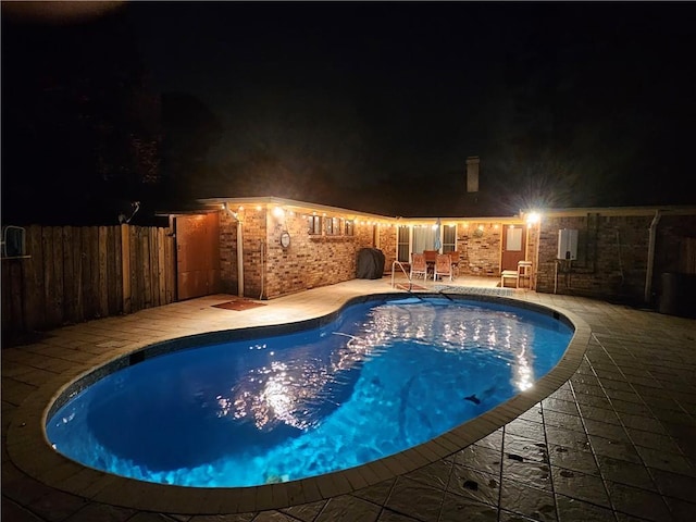 pool at twilight featuring a patio area