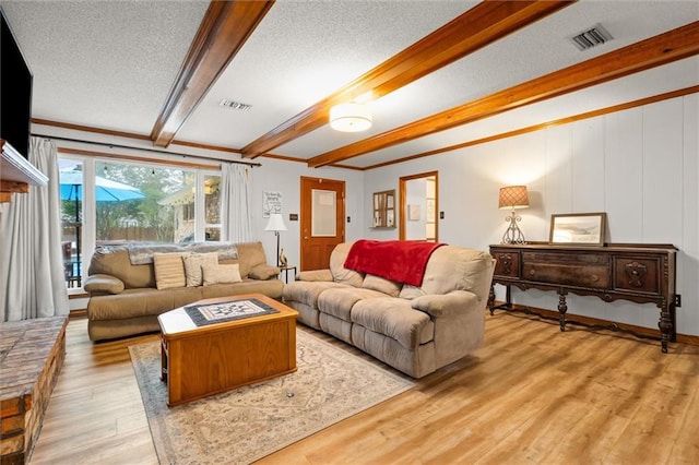 living room with light hardwood / wood-style floors, a textured ceiling, ornamental molding, and beamed ceiling