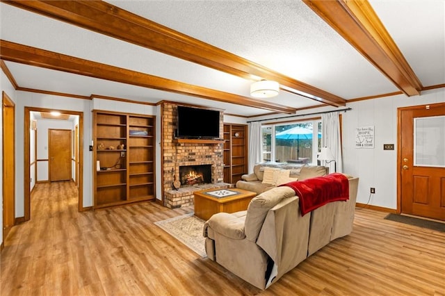 living room featuring light hardwood / wood-style floors, a fireplace, a textured ceiling, ornamental molding, and beamed ceiling