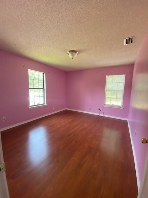 unfurnished room with dark wood-type flooring and a textured ceiling