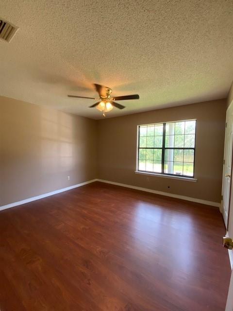 empty room with ceiling fan, dark hardwood / wood-style floors, and a textured ceiling