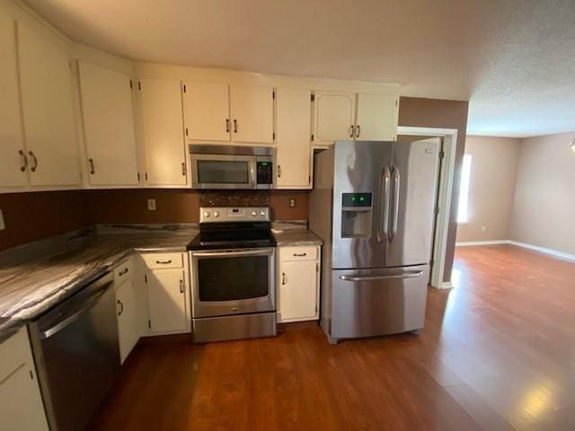 kitchen with stainless steel appliances, dark wood-type flooring, and white cabinets