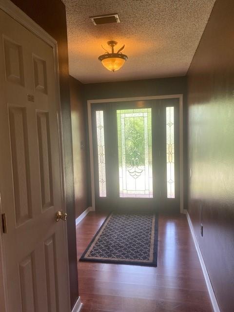 entrance foyer with a textured ceiling and dark hardwood / wood-style flooring