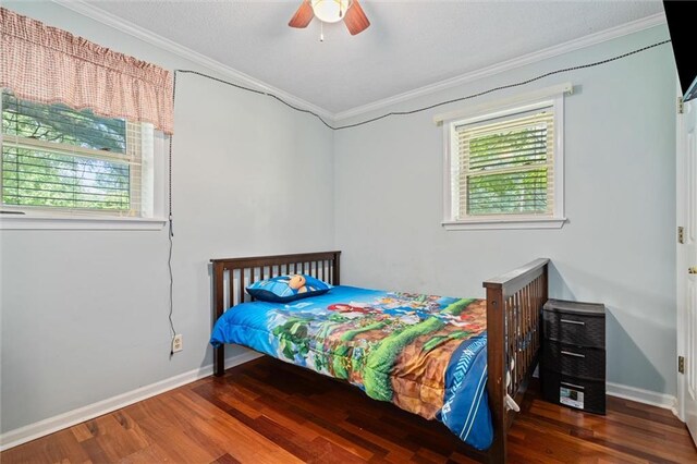 bedroom with ceiling fan, multiple windows, hardwood / wood-style floors, and ornamental molding