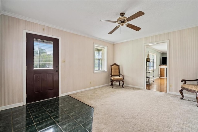 carpeted entryway featuring ceiling fan, plenty of natural light, and crown molding