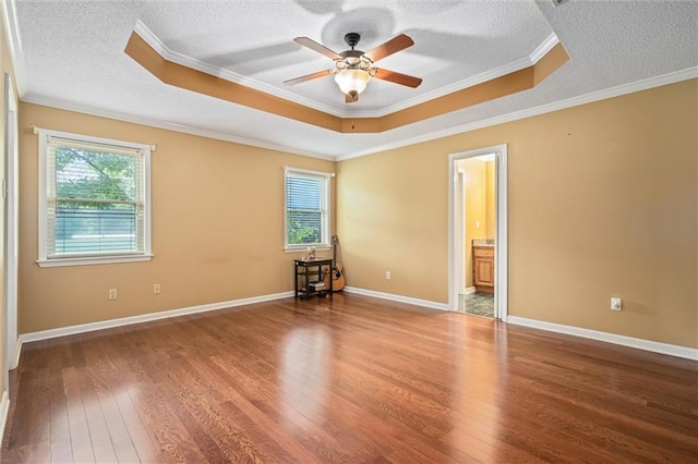 unfurnished bedroom featuring ceiling fan, crown molding, wood-type flooring, and a tray ceiling