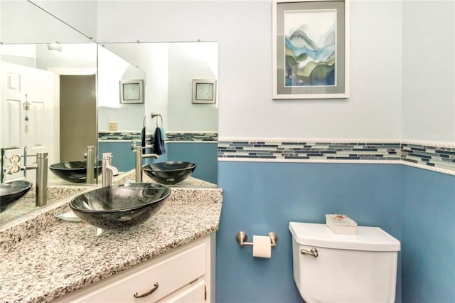 bathroom with vanity, toilet, and tile walls