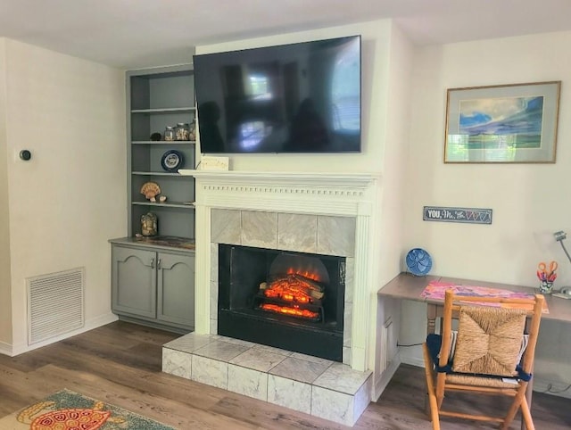 living room featuring a tile fireplace and dark wood-type flooring