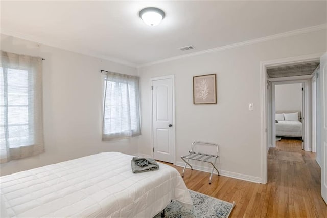 bedroom with light hardwood / wood-style flooring and crown molding