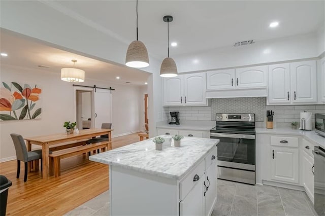 kitchen featuring a barn door, hanging light fixtures, white cabinets, appliances with stainless steel finishes, and a center island