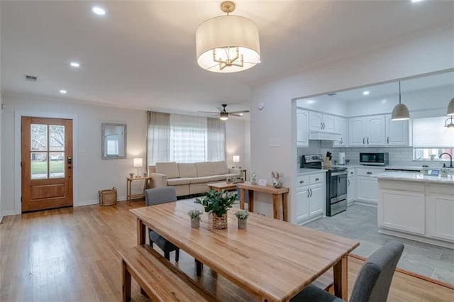 dining room featuring sink, light wood-type flooring, and ceiling fan