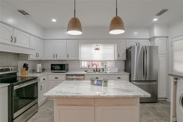 kitchen featuring light stone counters, decorative light fixtures, stainless steel appliances, and white cabinetry