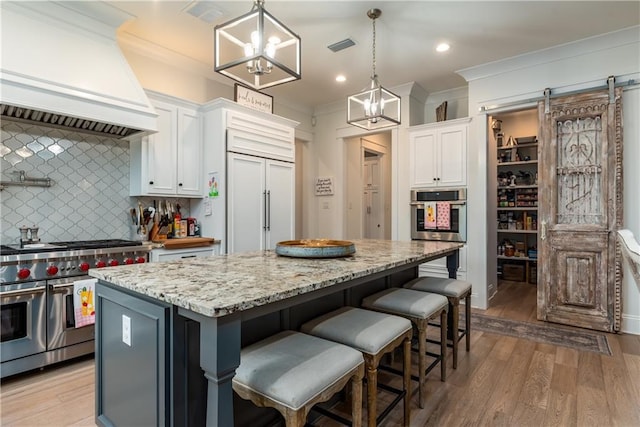 kitchen featuring a center island, high quality appliances, crown molding, white cabinetry, and custom range hood