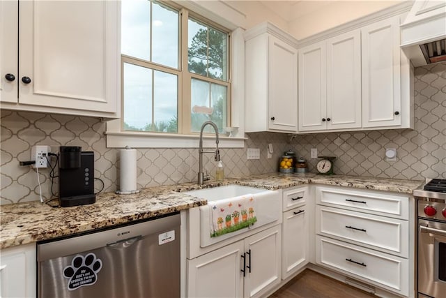 kitchen with a sink, white cabinets, light stone countertops, appliances with stainless steel finishes, and decorative backsplash