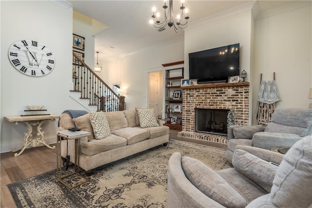 living area with wood finished floors, a fireplace, a chandelier, ornamental molding, and stairs
