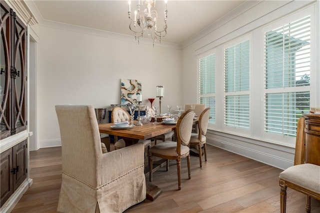 dining area with a wealth of natural light, a notable chandelier, crown molding, and light wood-style floors
