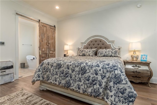 bedroom with recessed lighting, a barn door, baseboards, crown molding, and wood finished floors