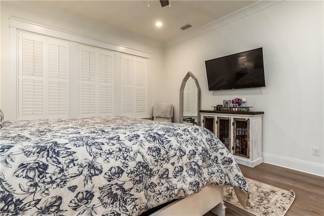 bedroom with ornamental molding, baseboards, visible vents, and wood finished floors