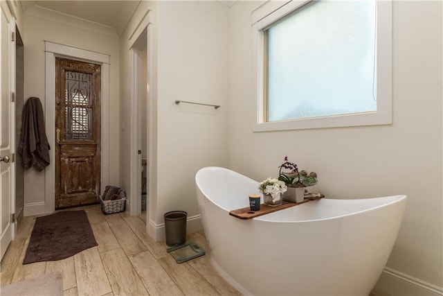 bathroom with baseboards, a freestanding bath, and wood finished floors