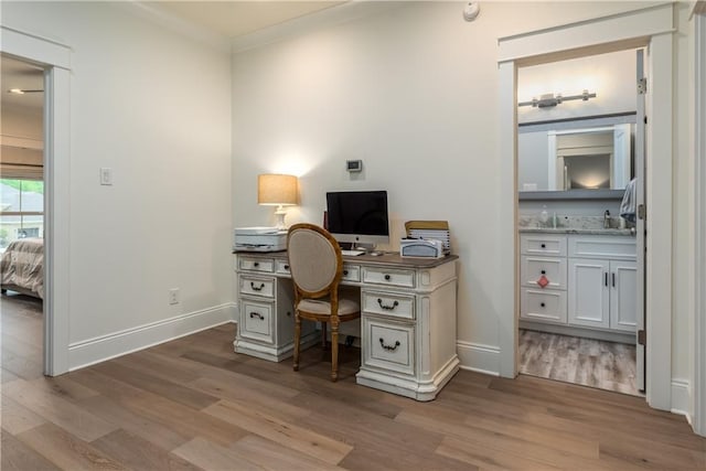 home office with light wood-style flooring, baseboards, and ornamental molding