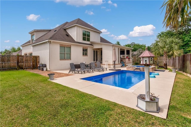 back of property with a patio, an in ground hot tub, a lawn, and a fenced backyard