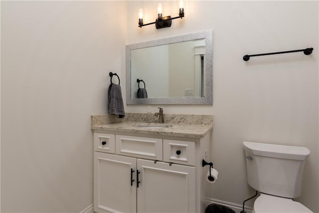 half bath featuring vanity, toilet, and baseboards